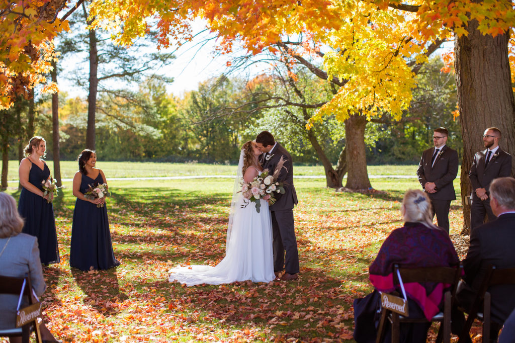 A bride and groom share a kiss during an autumn wedding theme ceremony