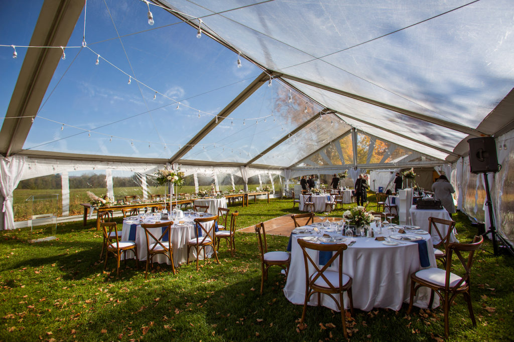 A sunny blue sky shines through an outdoor wedding tent during a Fermanagh Farms wedding in Toronto