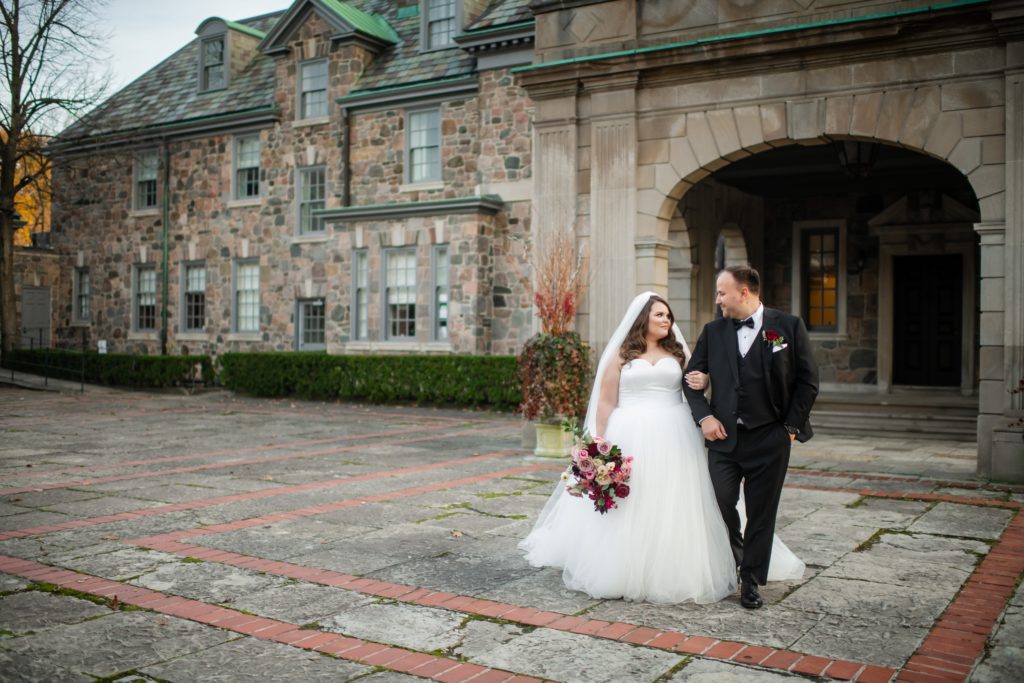 A couple stands in front of Graydon Hall for their winter wedding in Toronto