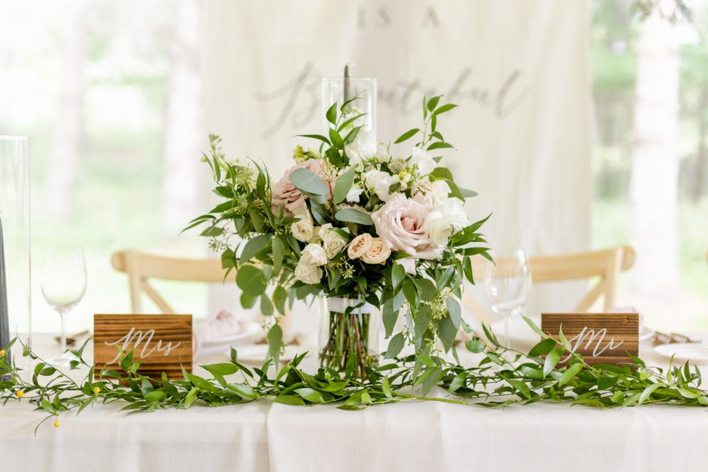 A beautiful floral centerpiece rests on a reception table during an outdoor wedding in toronto